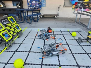 VEX IQ Rapid Relay competition field with yellow balls and student-built robots on display at a school event.